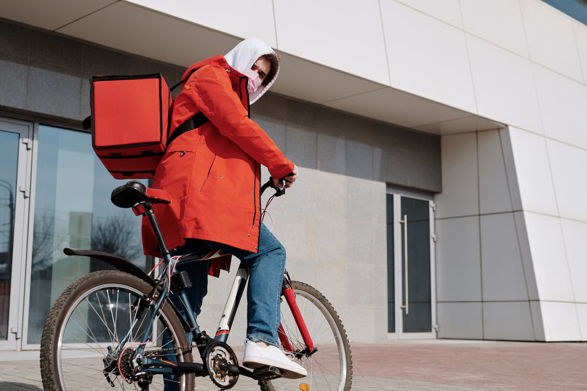 delivery man with a face mask riding a bicycle