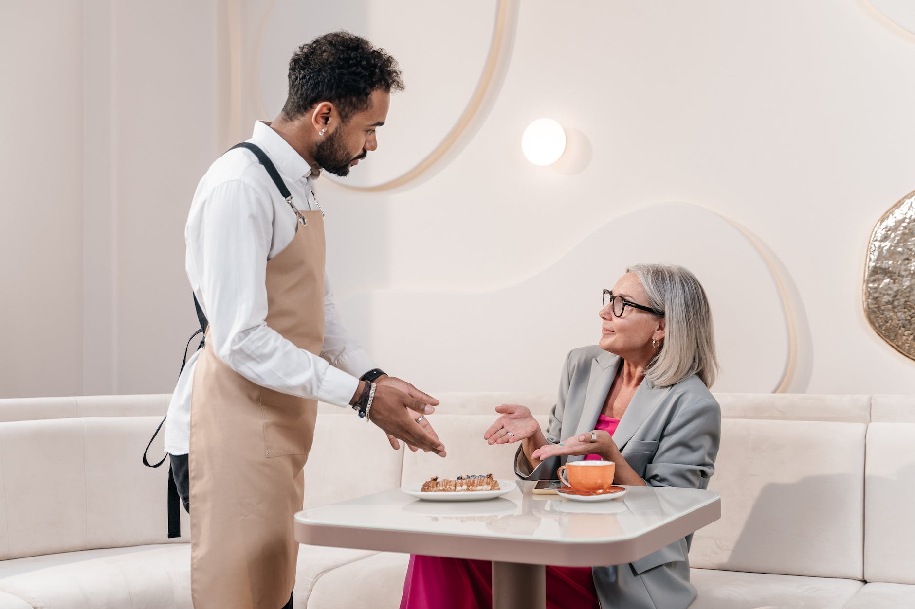 waiter and customer in a hotel restaurant pointing a dessert